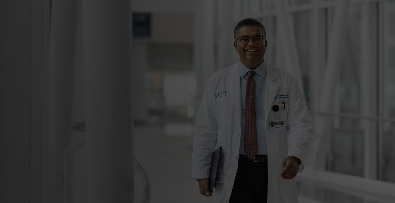 Un medico cammina con un MacBook sotto il braccio destro.