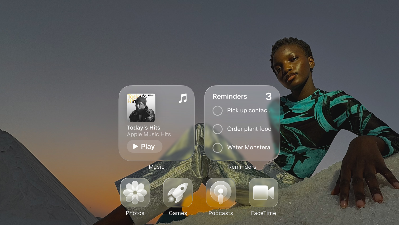 Liquid Glass-skærm med gennemsigtige appikoner, bl.a. Apple Music, Påmindelser, Fotos, Spil, Podcasts og FaceTime. Skærmbaggrunden kan anes gennem ikonerne