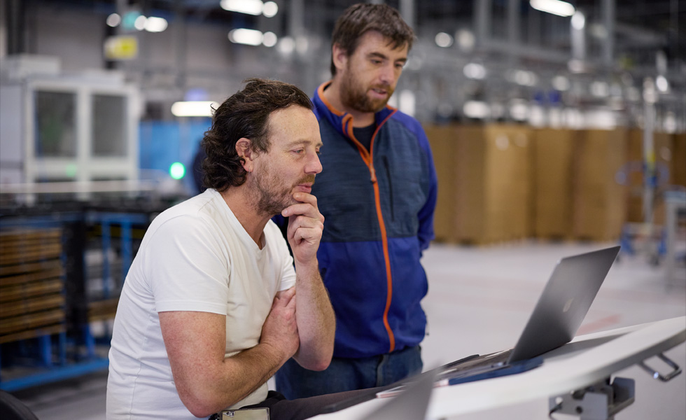 Two people share a laptop, collaborating or learning